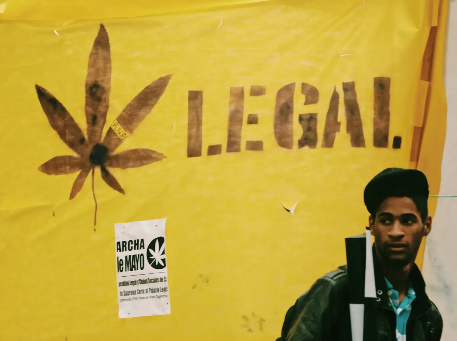 Gelbes Plakat mit Hanfblatt, Schriftzug 'LEGAL.' und einem Mann rechts