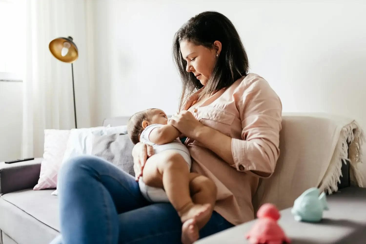 Mutter sitzt auf Sofa und stillt ihr Baby