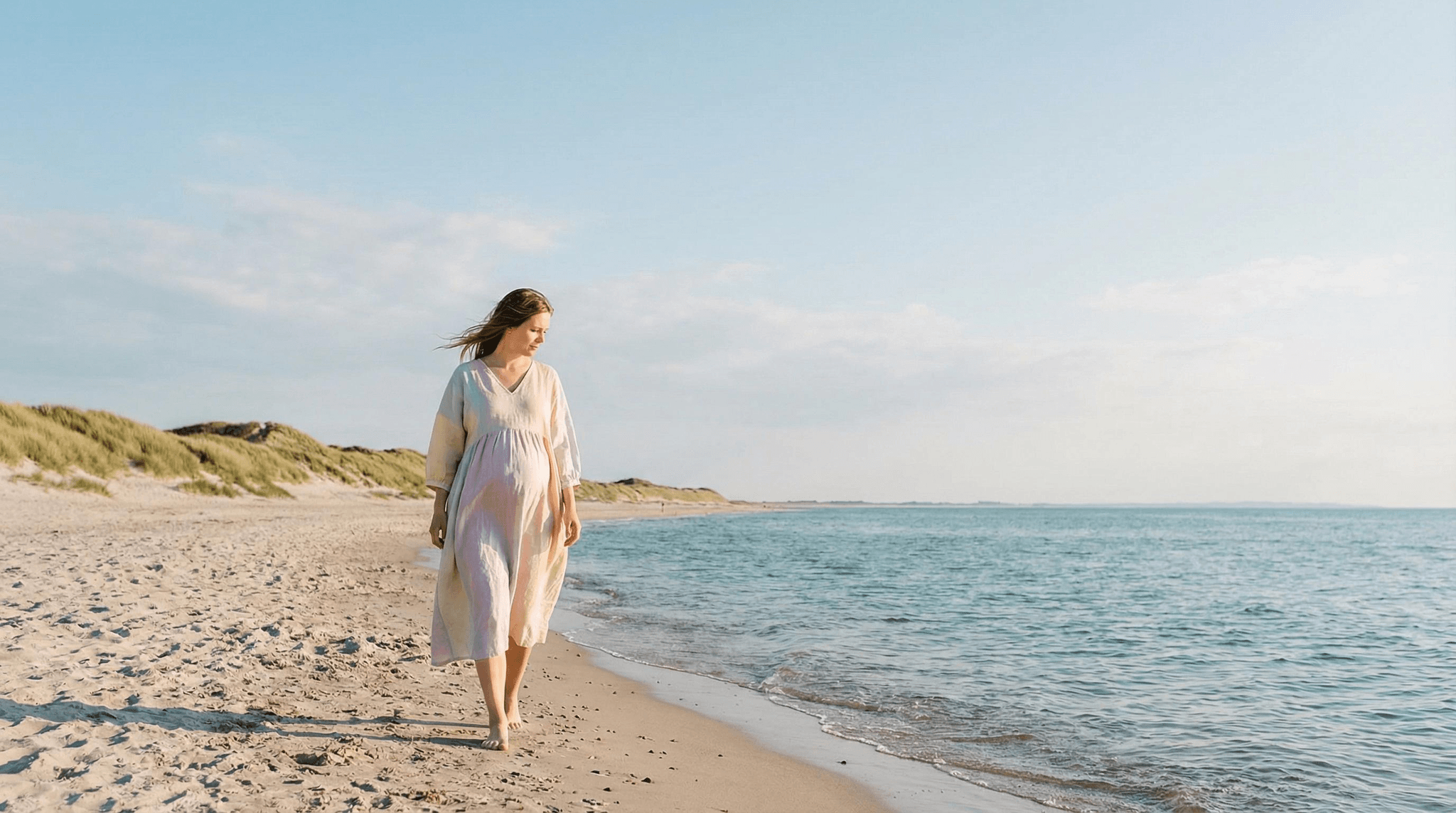 Schwangere Frau spaziert barfuß am Strand entlang – symbolisch für die Frage, welche Mittel in der Schwangerschaft sicher sind und welche Vorsicht erfordern.