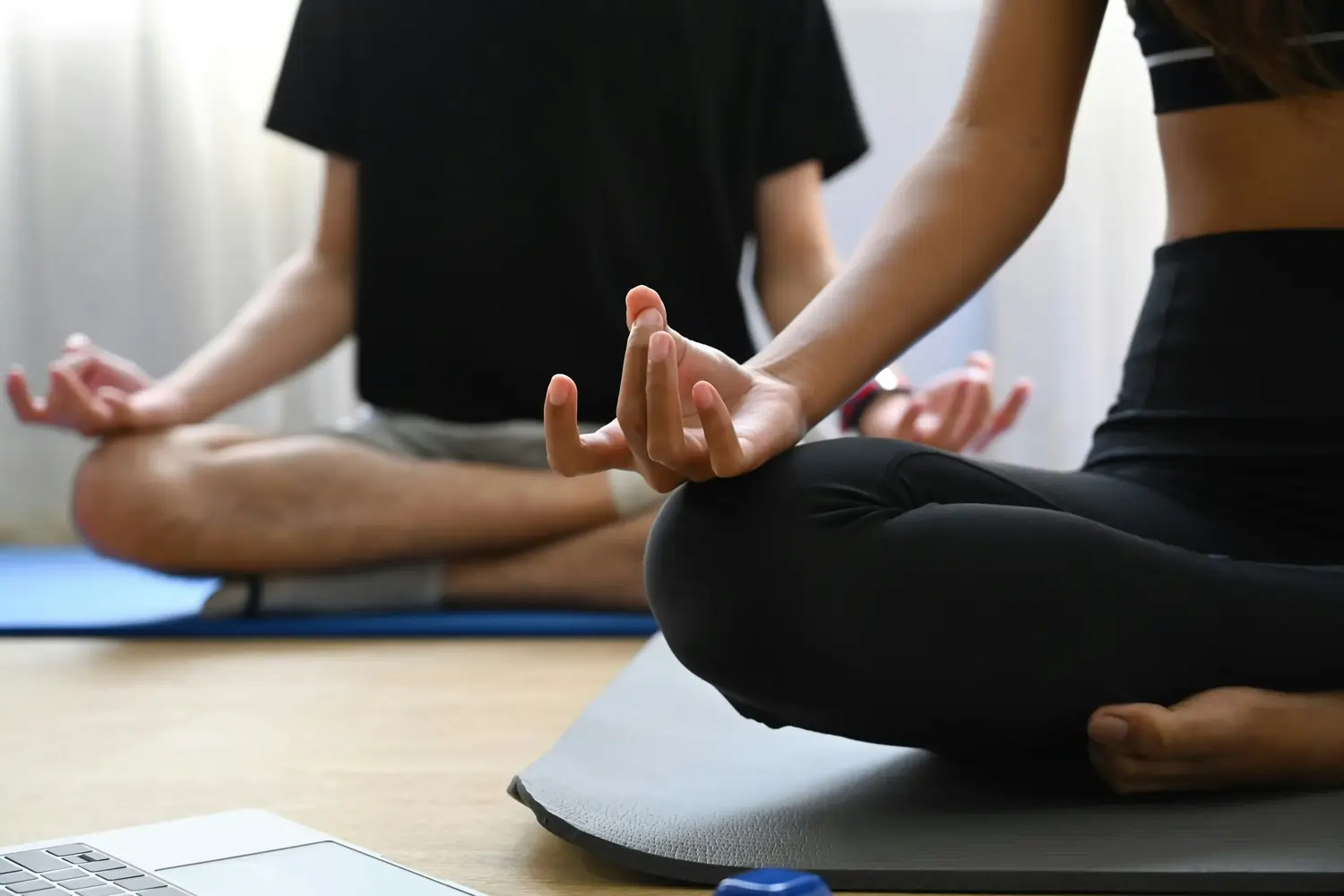 Zwei Personen im Schneidersitz, Hände in Gyan-Mudra auf Yogamatten