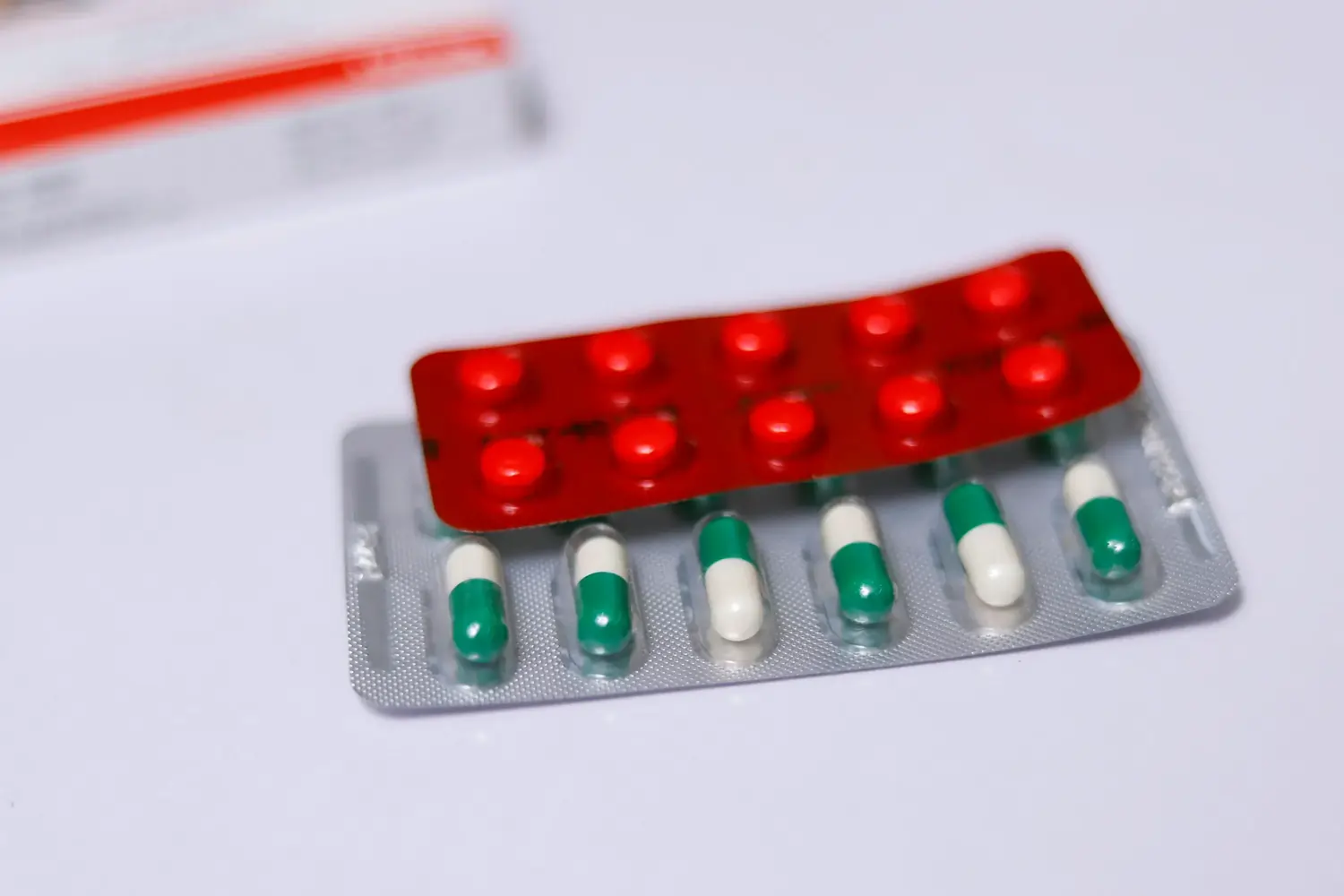 Blister mit grün-weißen Kapseln und rotem Tablettenblister