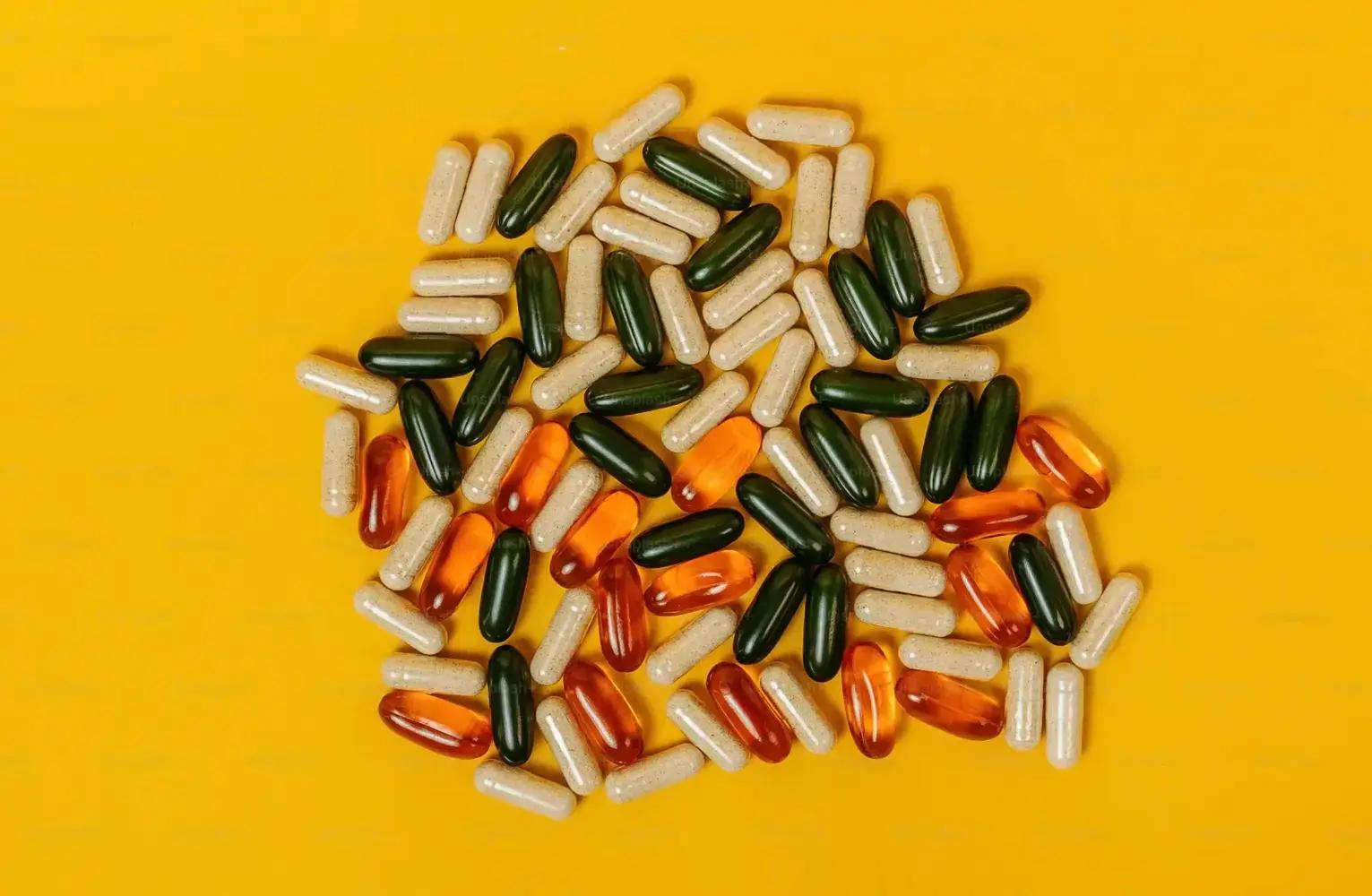 Beige, dunkelgrüne und orange Kapseln auf gelbem Hintergrund