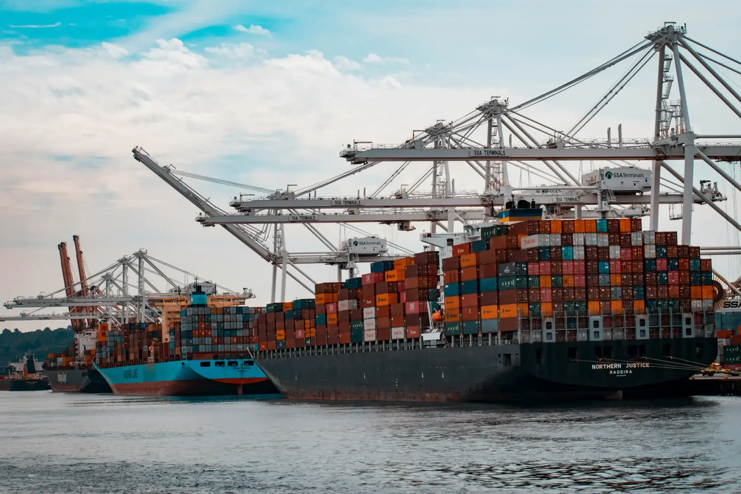 Mehrere Containerschiffe und Kräne am Hafen mit gestapelten Frachtcontainern
