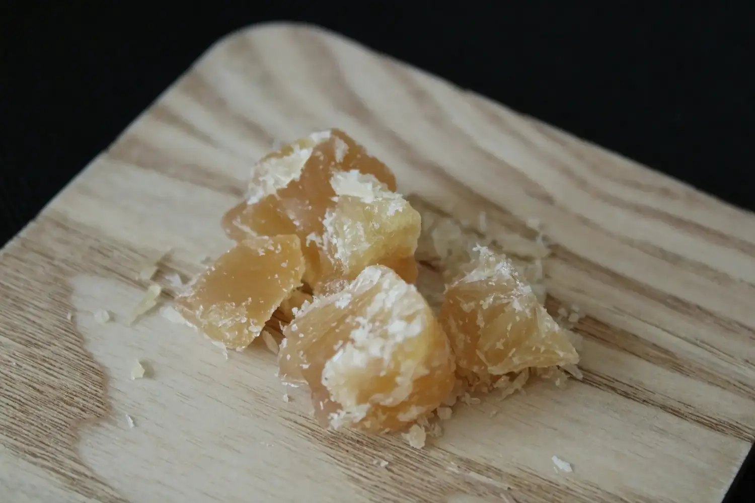 Gelbliche Harzklumpen mit weißen Kristallen auf Holzbrett