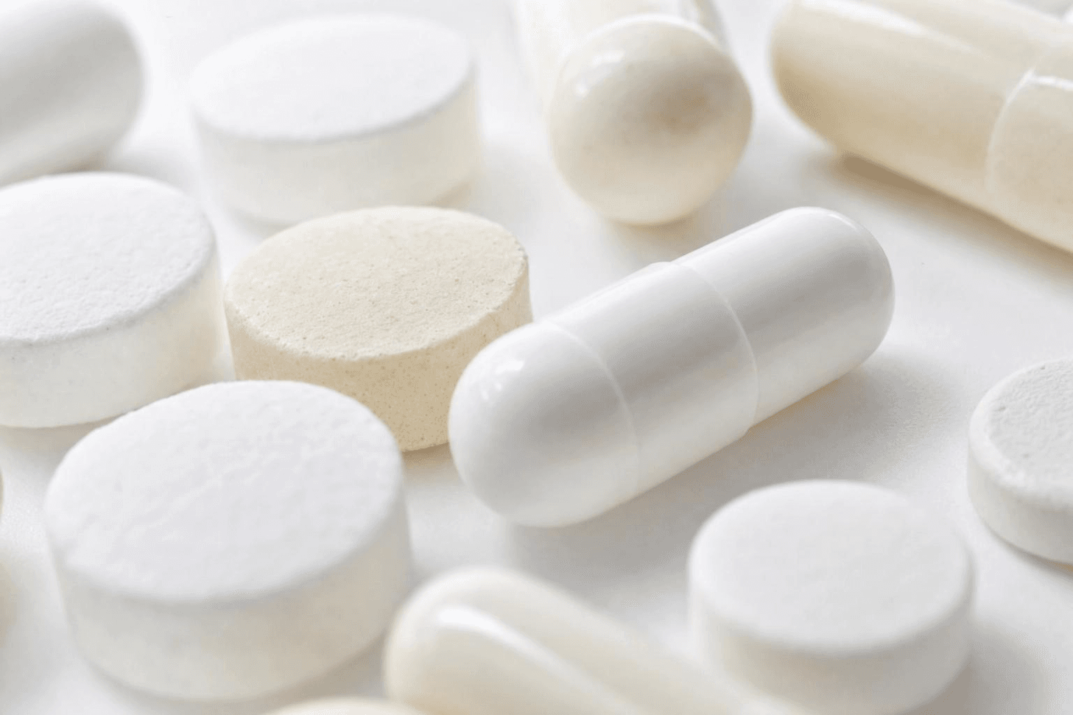 Weiße Schmerztabletten und Weichgelkapseln in Nahaufnahme