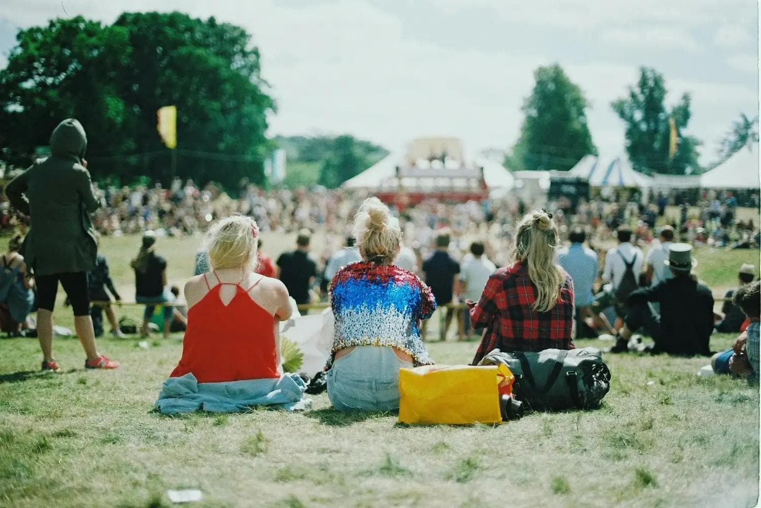 Drei Frauen sitzen im Gras auf einem Festival.