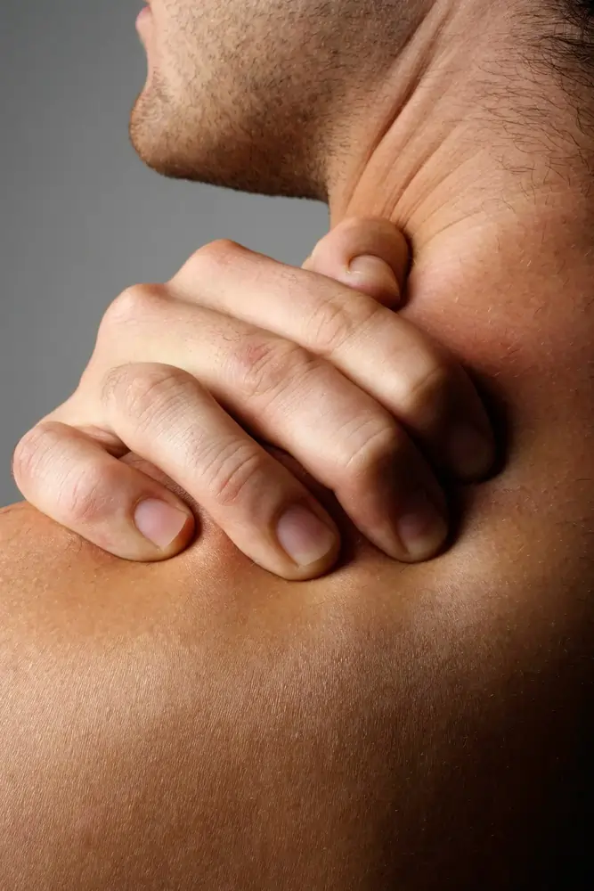 Hand greift Nacken und Schulter, Muskelspannung sichtbar