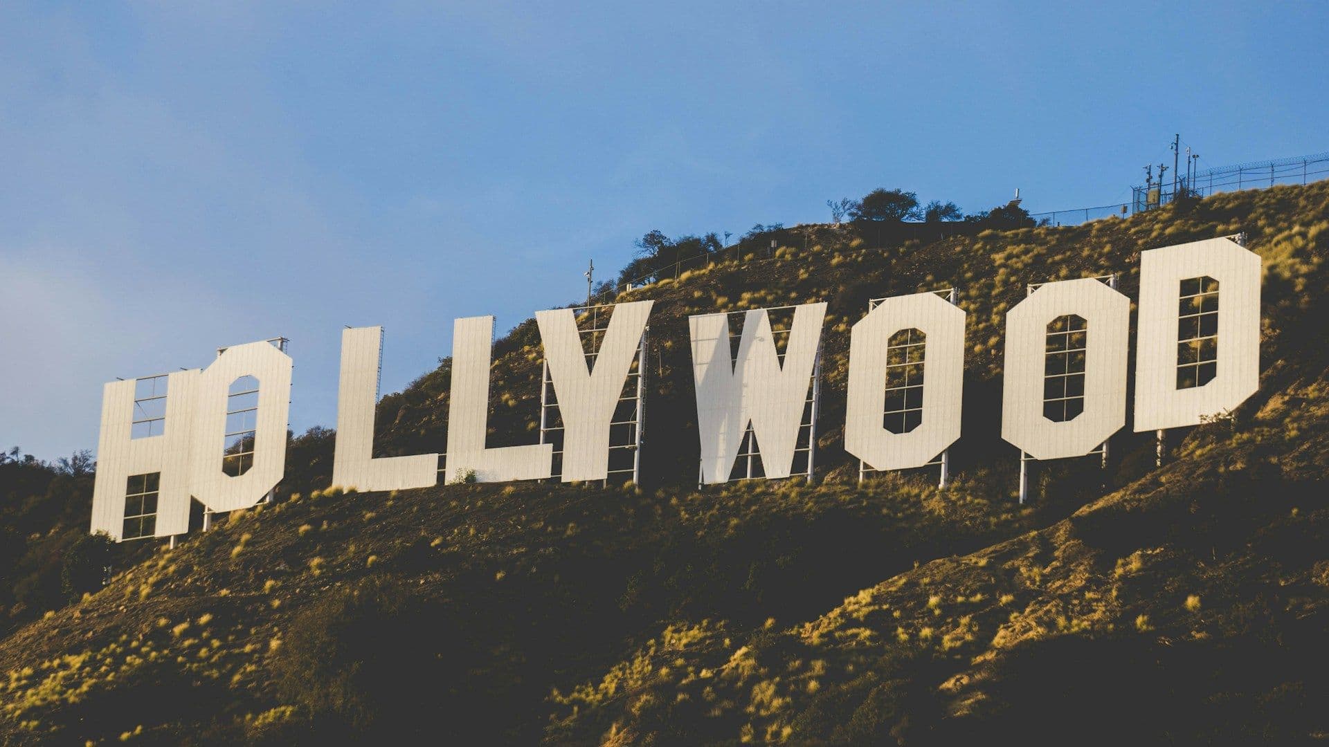 Weißer Hollywood-Schriftzug auf sonnigem Hügel vor blauem Himmel