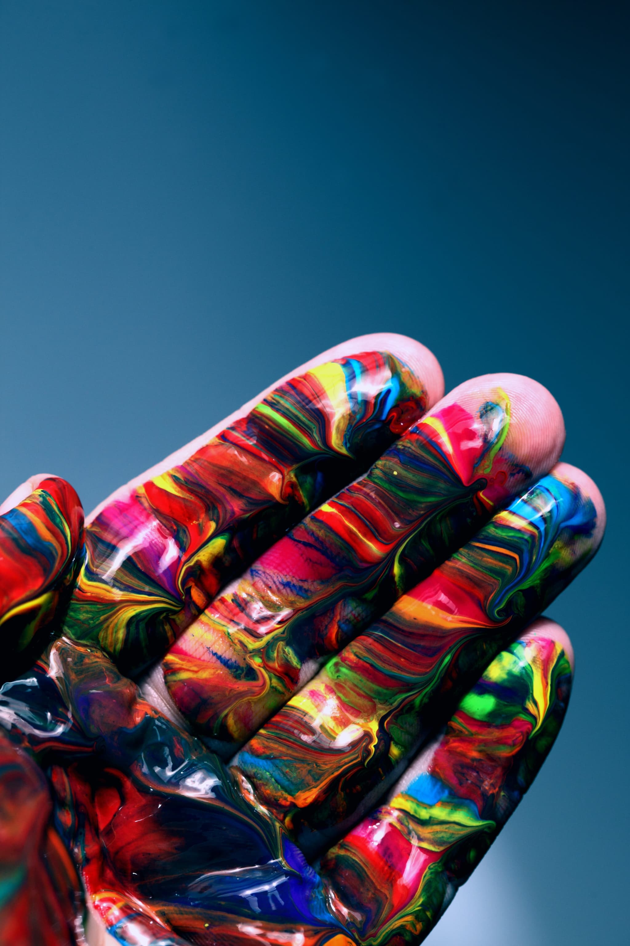 Nahaufnahme einer Hand mit verschmierten, bunten Acrylfarben