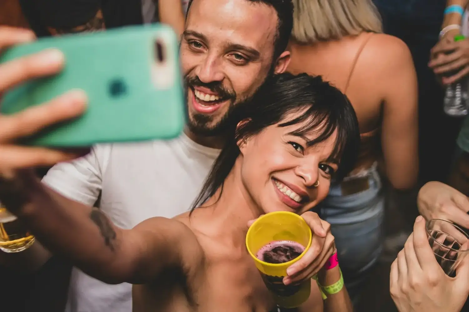 Lächelndes Paar beim Selfie im Club, Frau mit gelbem Becher