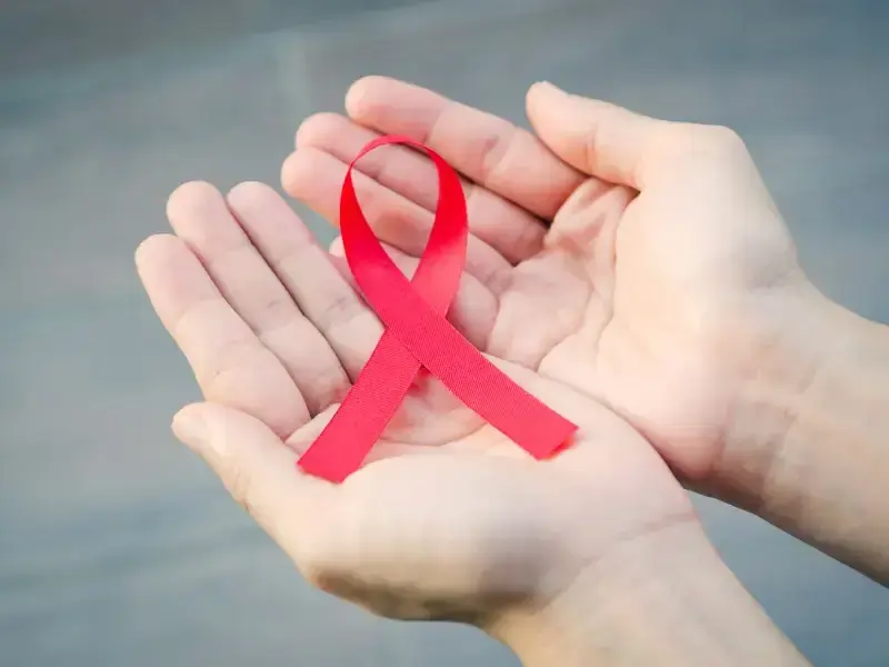 Offene Hände halten rote Aids-Schleife