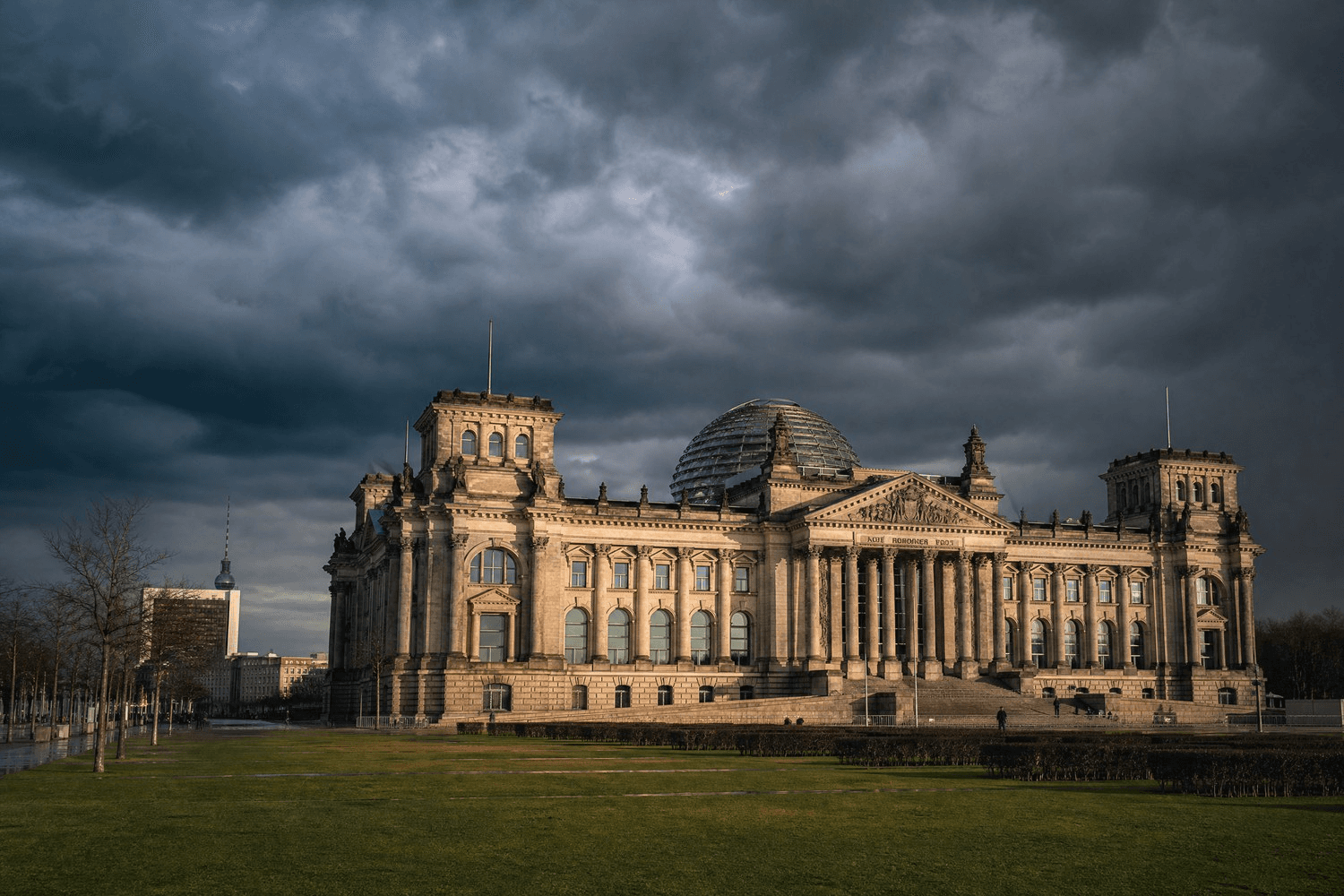 Reichstagsgebäude in Berlin unter dunklen Wolken als Symbolbild für die gesetzliche Neuregelung der GKV-Erstattung von Cannabisblüten.