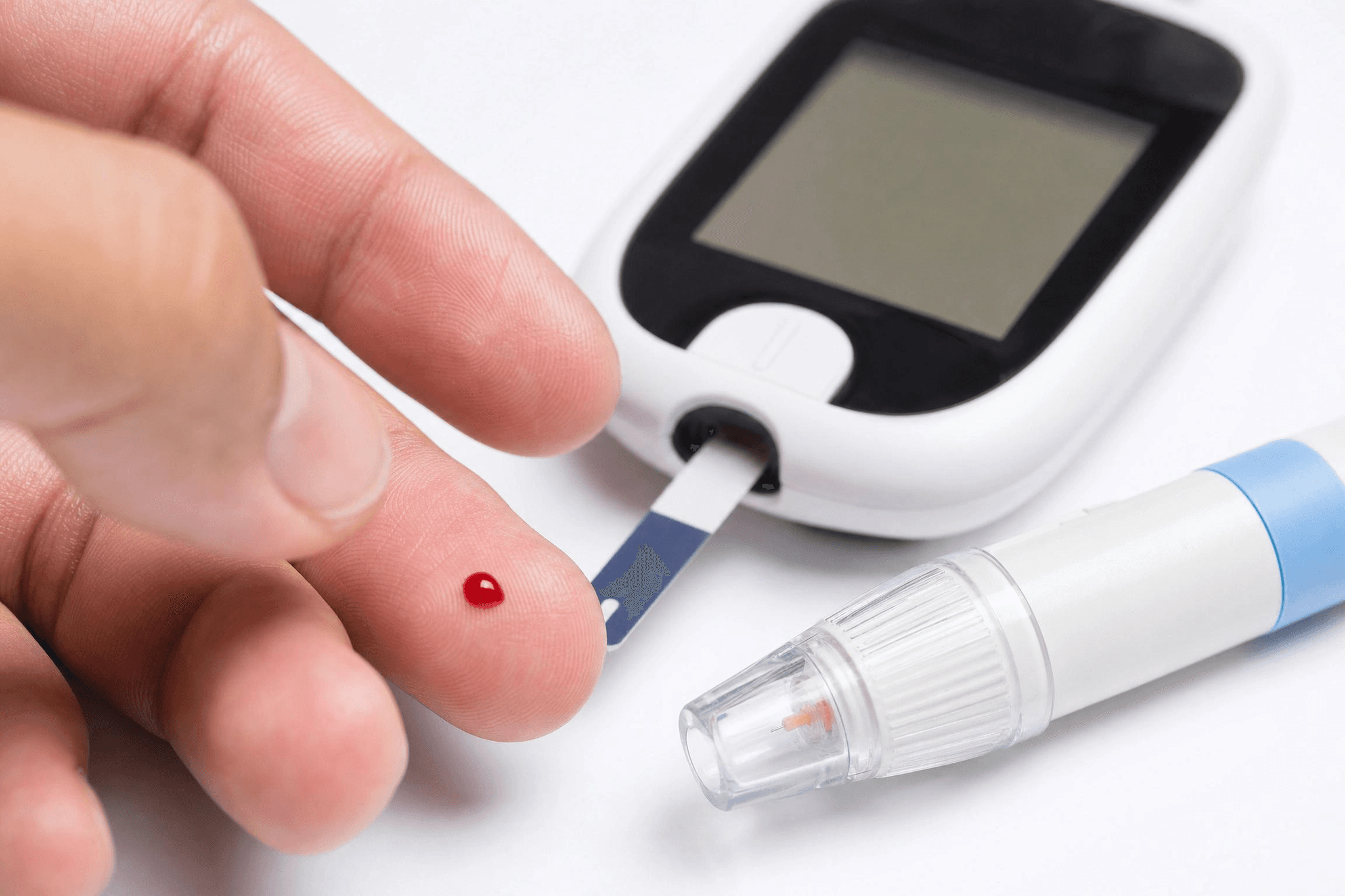 Nahaufnahme einer Blutzuckermessung: Finger mit Bluttropfen wird an ein Blutzuckermessgerät mit Teststreifen gehalten – Blutzuckerkontrolle bei Diabetes