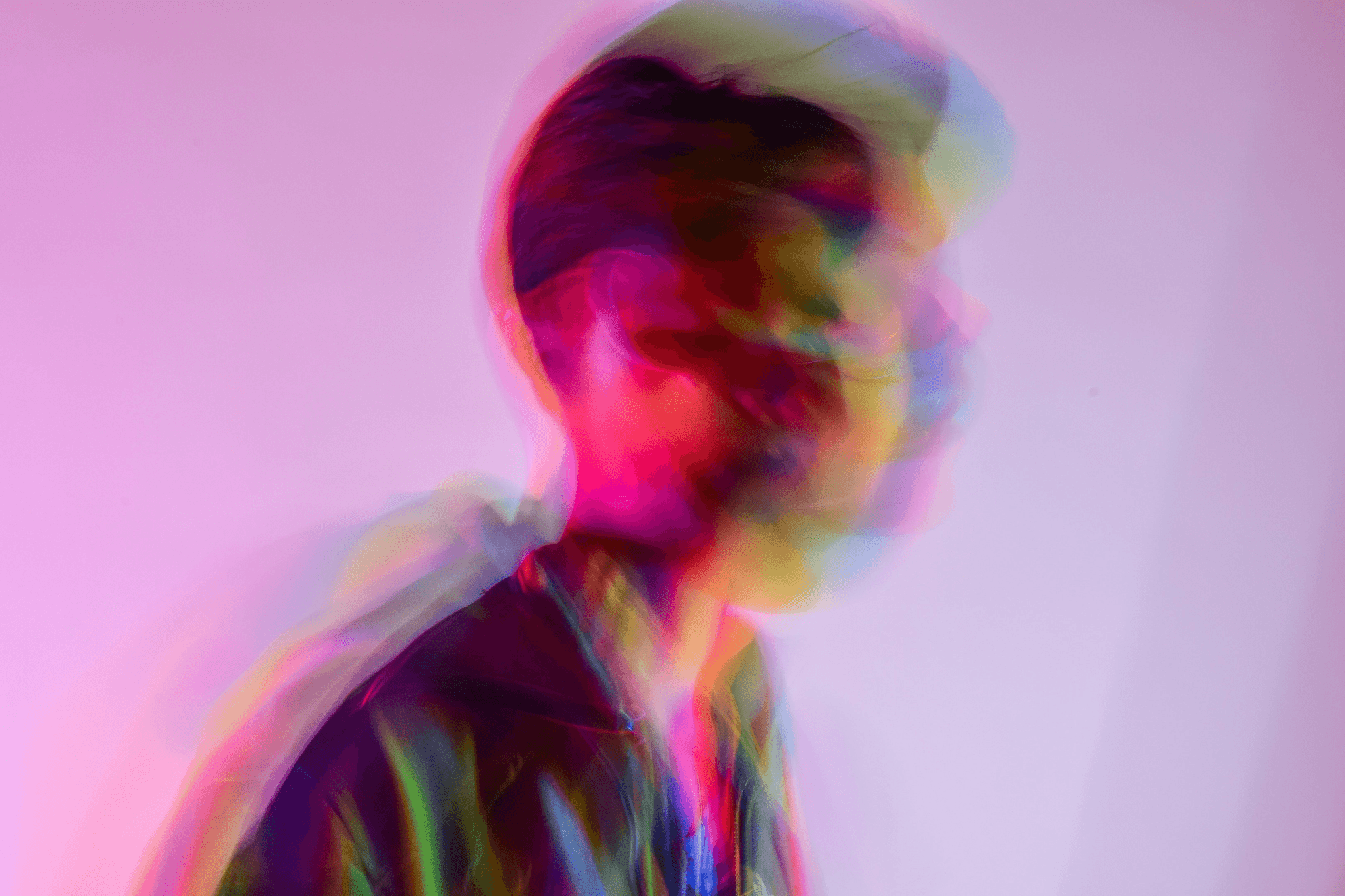 Verschwommene Silhouette einer Person mit Hand am Kopf, überlagerte Farbverläufe in Pink, Gelb, Grün, Blau, psychedelischer Effekt